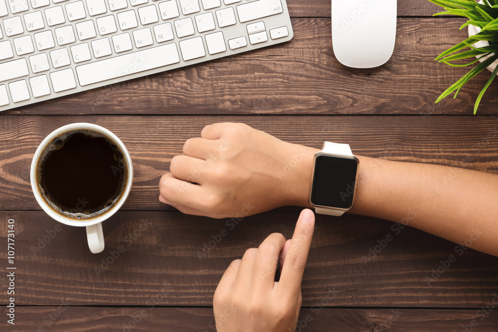 Poster hand using smartwatch on desk top view