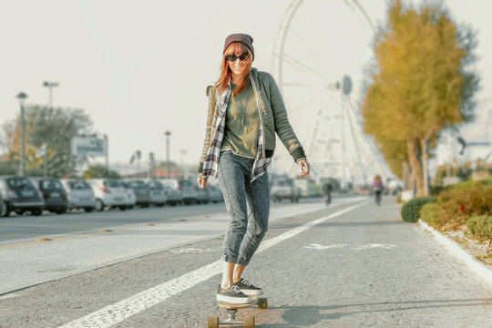 pretty girl on skate board in action - modern urban hipster girl in fashionable clothes and  skateboarding on street - custom colors and selective focus on her perfect body and stylish clothes