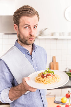 Happy smiling man or chef holding plate with spaghetti