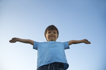 boy with widely placed hands on background of the sky