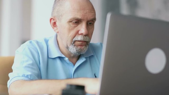 Senior man works with laptop