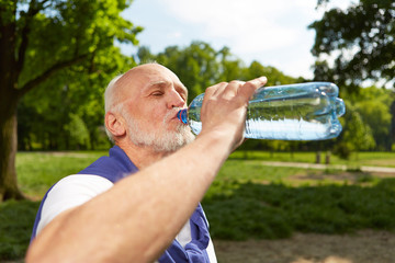 Senior trinkt Flasche Wasser nach dem Sport