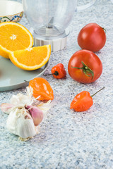 Ingredients for chili sauce. Orange, tomatoes, garlic, chili peppers.