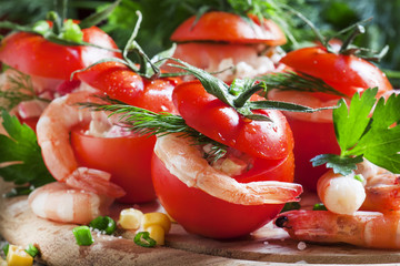 Tomatoes stuffed with shrimp meat and corn on a wooden plate, se