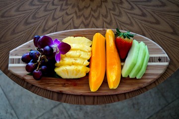 Tropical fruit platter presented on a wooden surfboard