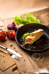 Composition of hot roll on cast-iron pan and vegetables