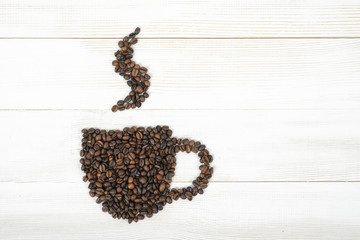 Cup of fragrant hot coffee made by beans on wooden background