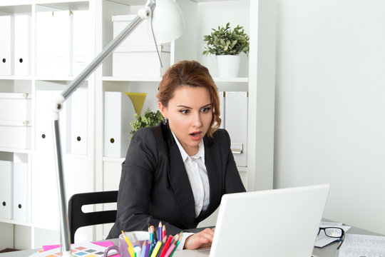 Portrait of surprised businesswoman looking at laptop screen