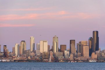 Naklejka premium Seattle Skyline at Sunset. During a beautiful Seattle, Washington sunset ferry boats run between Bainbridge Island and downtown Seattle. Modern skyscrapers line the waterfront.