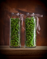 Peas in glass jars on wooden box and dark background