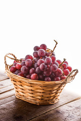 Red grapes in basket on wooden old rustic table and white background