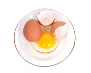 Cracked brown eggs on plate separated on white background