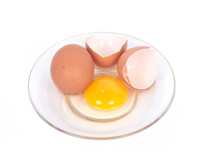 Cracked brown eggs on plate separated on white background
