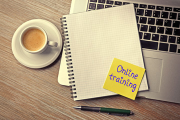 Online training written on sticky note, laptop, notebook and cup of coffee on table, top view