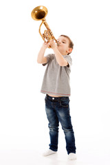 young boy blowing into a trumpet against white background