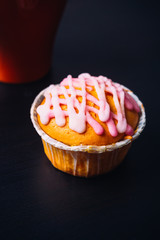 cupcake with pink frosting and red cup on a wooden background