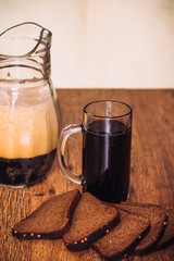 Russian brew in mug  jug and loaf of rye flour on wooden background