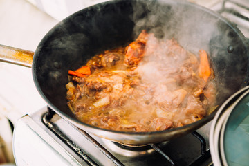 chicken in sauce with carrots on a pan closeup