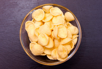 Potato snacks on bowl on slate top seen from above