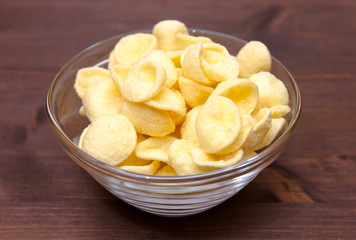 Potato snacks on bowl on wooden table