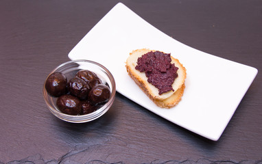 Slice of bread with olive paste on top in slate