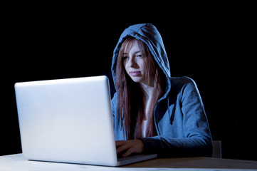 young attractive teen woman wearing hood on hacking laptop computer cybercrime cyber crime concept