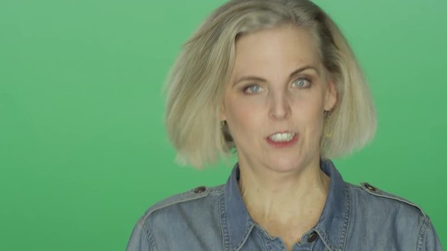 Beautiful older woman smiling and making silly faces, on a green screen studio background