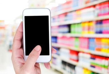 Hand holding smart phone over blur store background