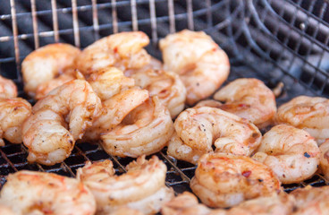 Large mouth watering seasoned wild caught shrimp being grilled over charcoal in a grill basket