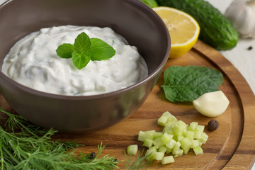 Tzatziki sauce in a bowl and ingredients close-up