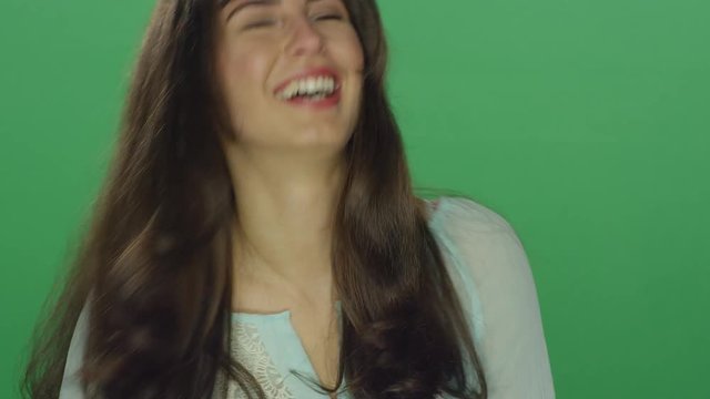 Beautiful brunette woman laughing and smiling, on a green screen studio background