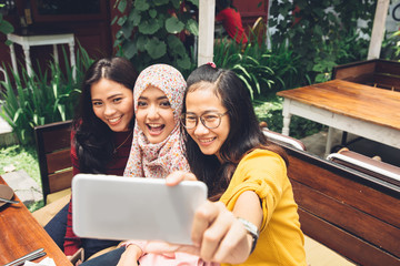 Friendly girls making selfie in cafe