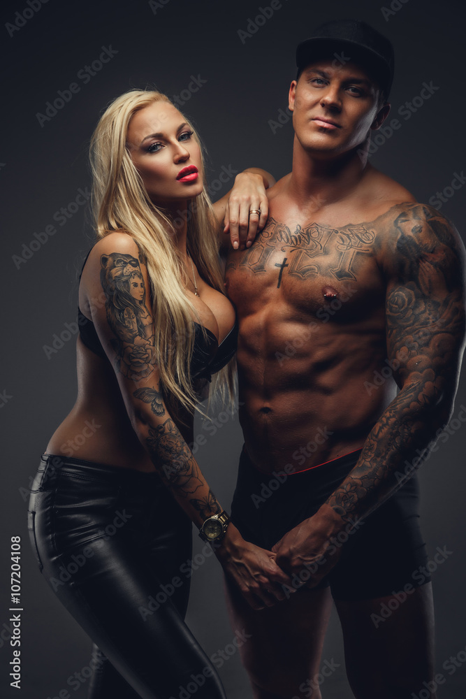 Wall mural Modern tattooed couple posing in a studio.