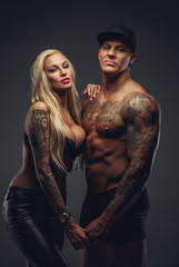 Modern tattooed couple posing in a studio.