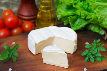 Brie cheese. Camembert cheese. Fresh Brie or Camembert cheese with basil leaves. Italian, French and Mediterranean ingredients.
