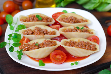 pasta shells stuffed with minced beef meat with herbs and tomato sauce on a plate