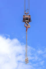 Metal crane hook  against the background of the blue sky with the clouds