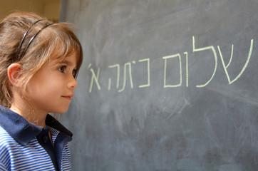 Little girl reads Hello First Grade greetings in Hebrew