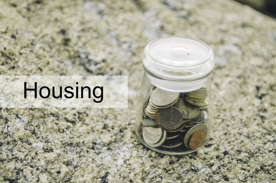 Financial image concept with word HOUSING. Blurred background coin in glass jar on the rock.