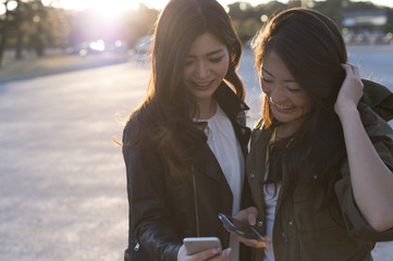 Two young women are laughing to see the smartphone together
