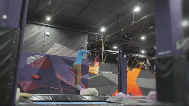 Professional Gymnast doing Tricks on Trampoline. Flips in Air. High Extreme Jumps by Professional Athlete.