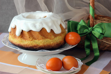 Easter cake on a plate and painted eggs on the table..