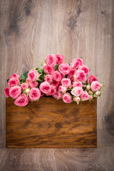 Roses in the box on wooden background