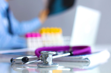 A medical stethoscope near a laptop on table, on white