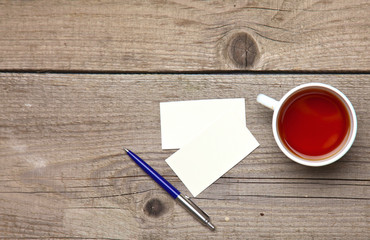 Blank business cards with pen and tea cup on wooden office table