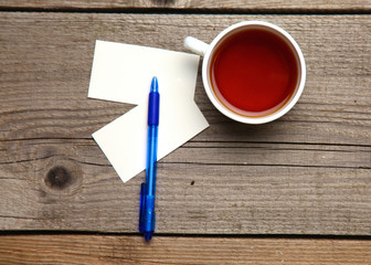 Blank business cards with pen and tea cup on wooden office table