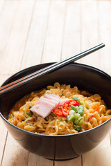 Korean noodles(Ramyun) in black bowl on wooden table.