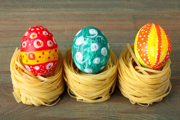Easter egg painted in different colors and lies on Italian pasta on wooden background