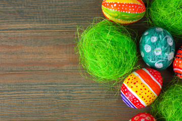 Easter egg in beautiful and different colors lie on the grass on wooden background