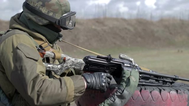 A soldier with a machine gun on a military firing range shooting at a target.